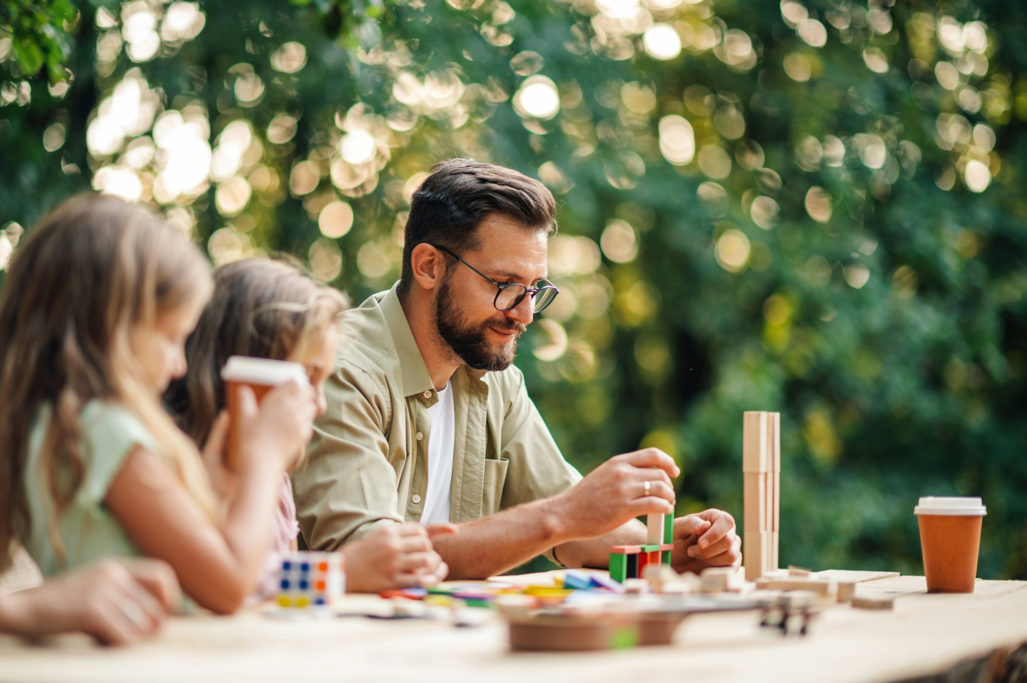 A father playing fun building a tower game in nature with children.