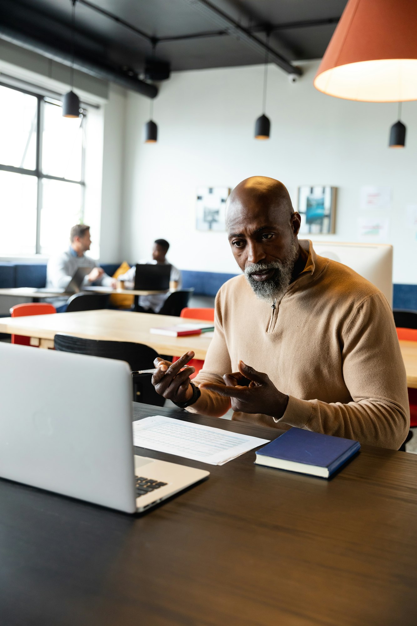 African american mature businessman video calling through laptop in creative office