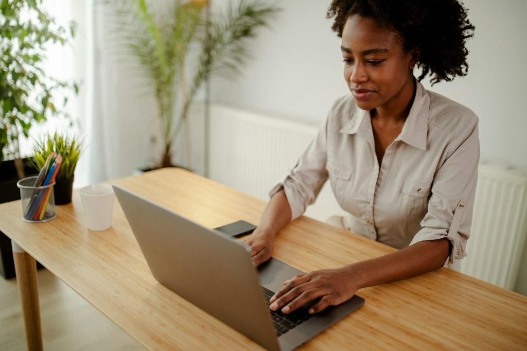 Concentrated afro american copywriter updating software on laptop computer in office.