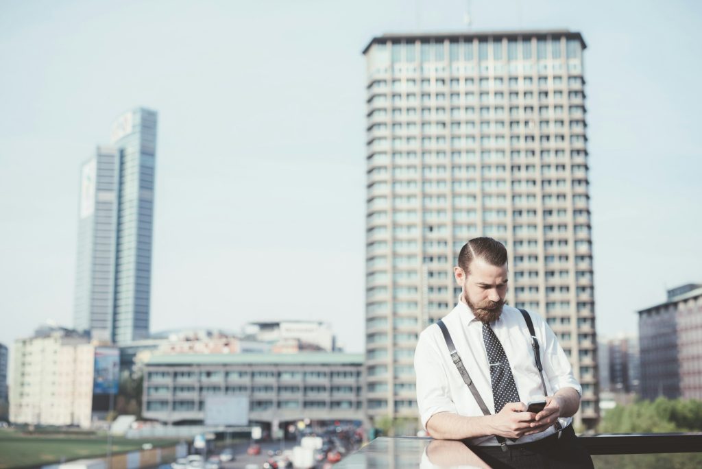 Stylish businessman reading smartphone text update on office balcony